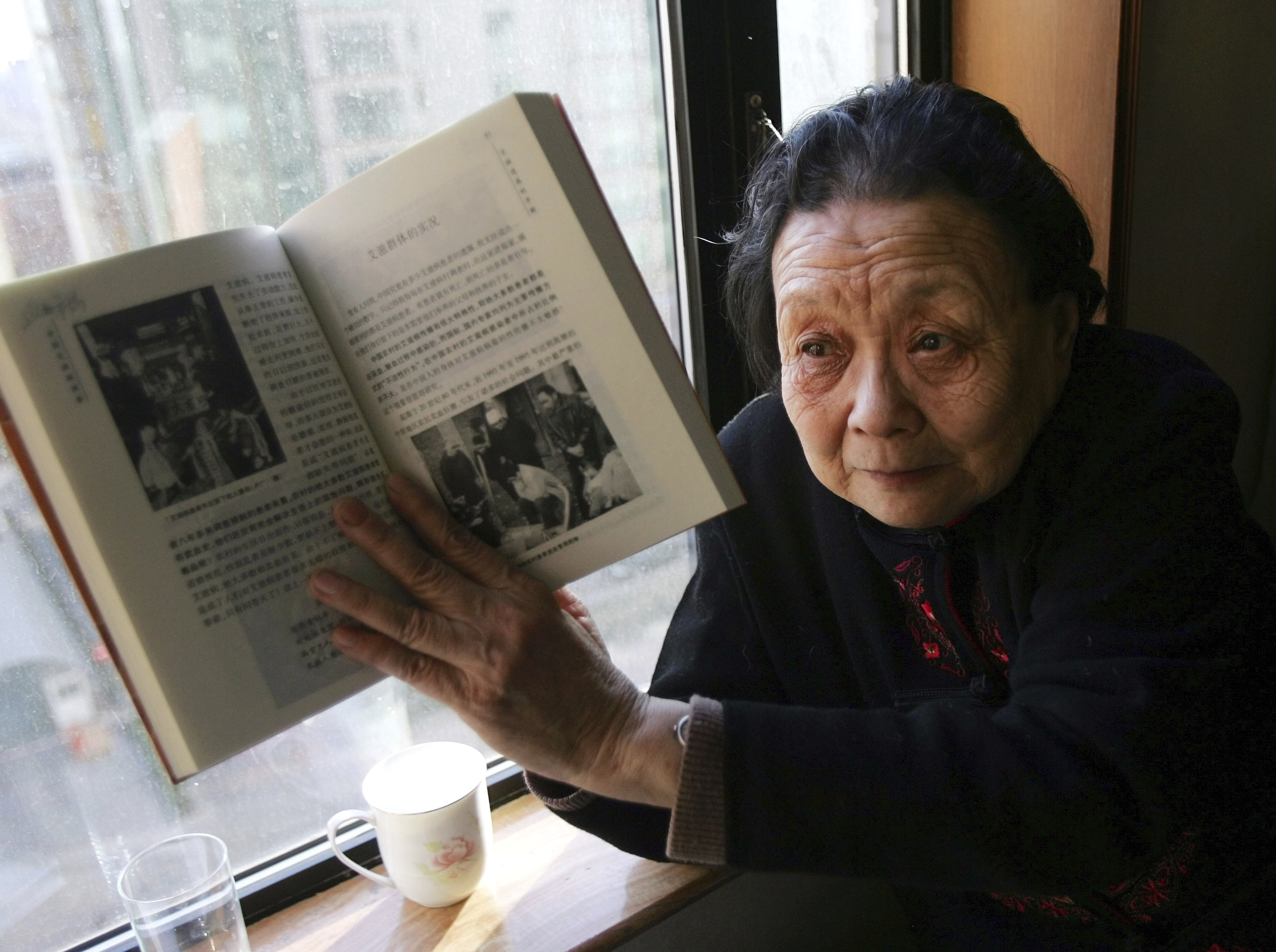 La activista contra el sida Gao Yaojie muestra un libro que escribió sobre el sida en China