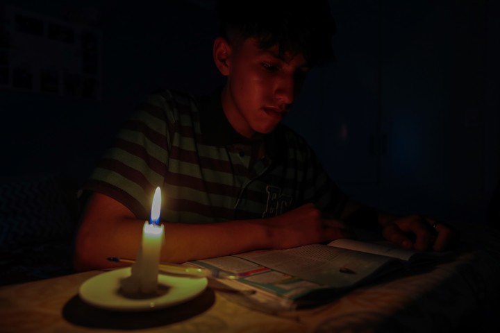 Un estudiante lee un texto a la luz de una vela en Quito (Ecuador). Foto EFE